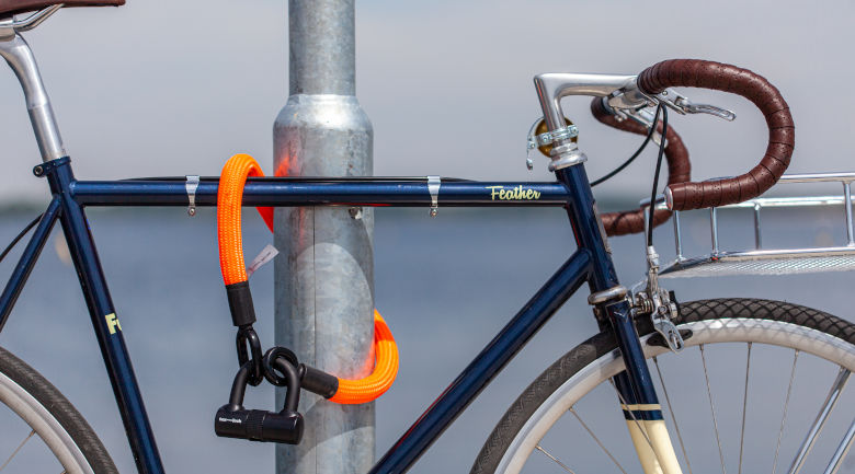 blaues fahrrad angeschlossen kurzes orangenes fahrradschloss laternenpfeiler