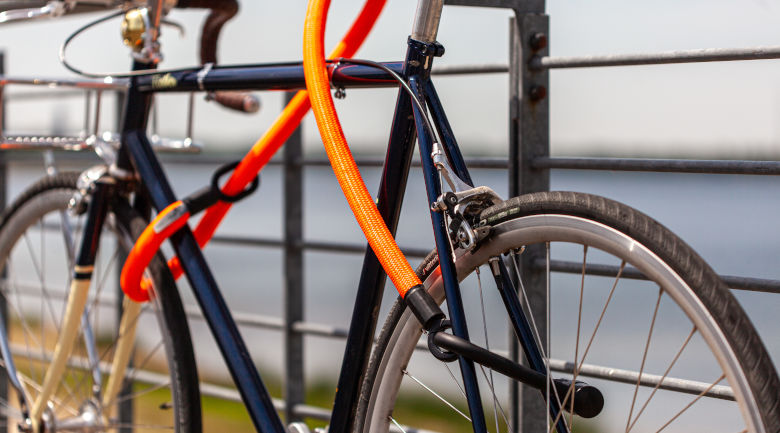 fahrrad blau langes textilfahrradschloss orange gesichert gelaender